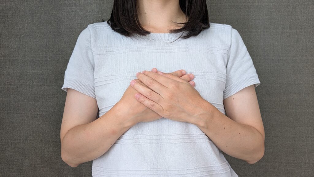 女性　胸に手を当てる
