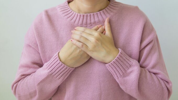 胸に手を当てる女性　ピンク色　顔なし