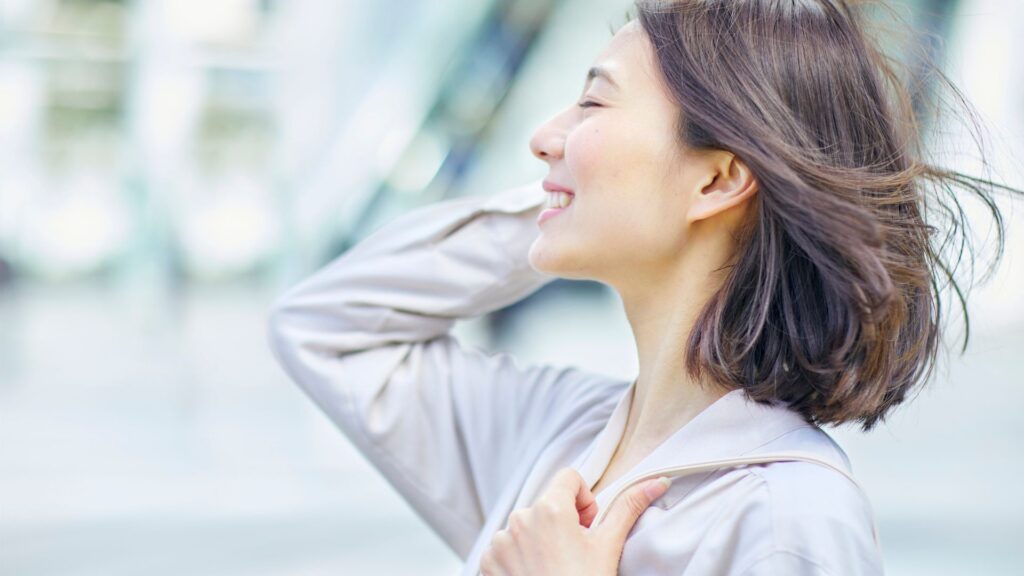 笑顔で髪かきあげる女性の横顔